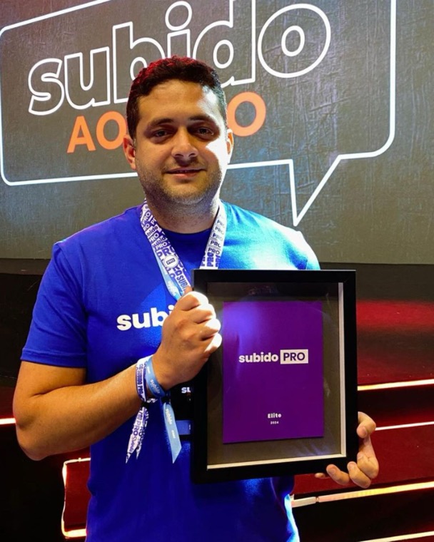 Élcio Souza segurando a placa Subido PRO Elite 2024 em evento de tráfego pago
